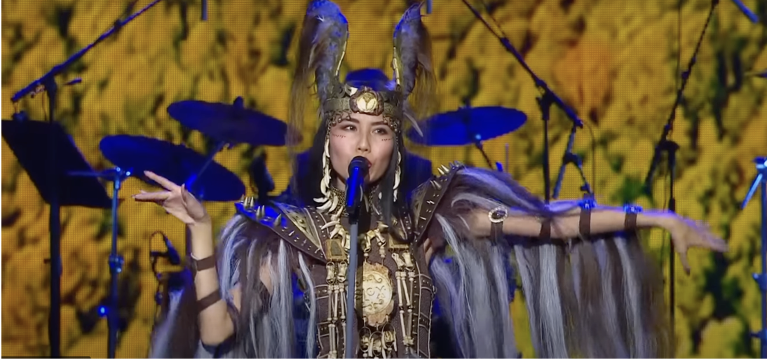Snow Raven, singer, in elaborate blue and gold costume singing at the microphone